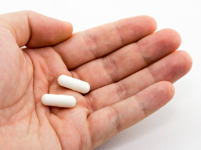 Two white capsules resting in an open palm