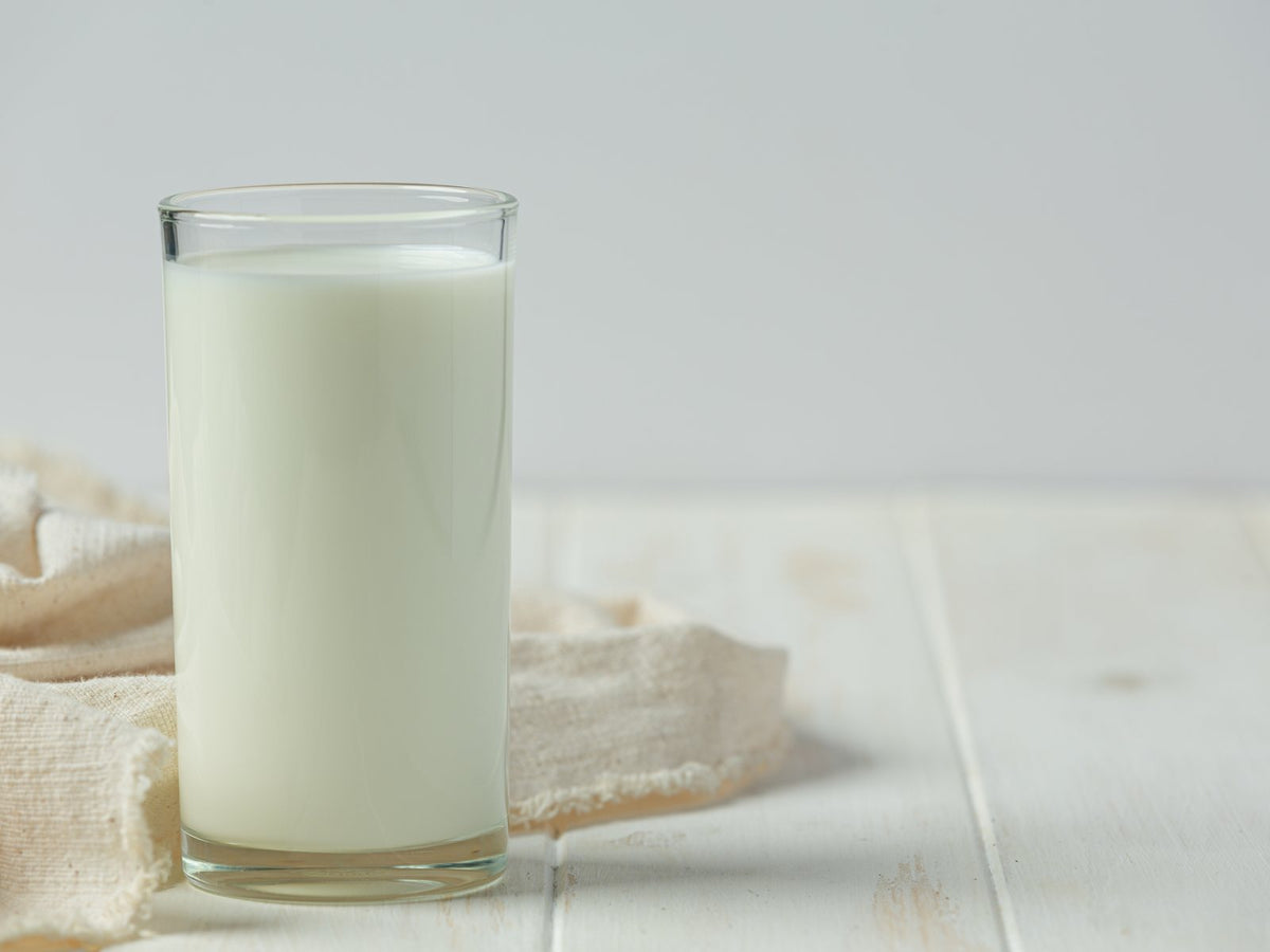 A glass of milk beside a linen cloth on a white wooden table
