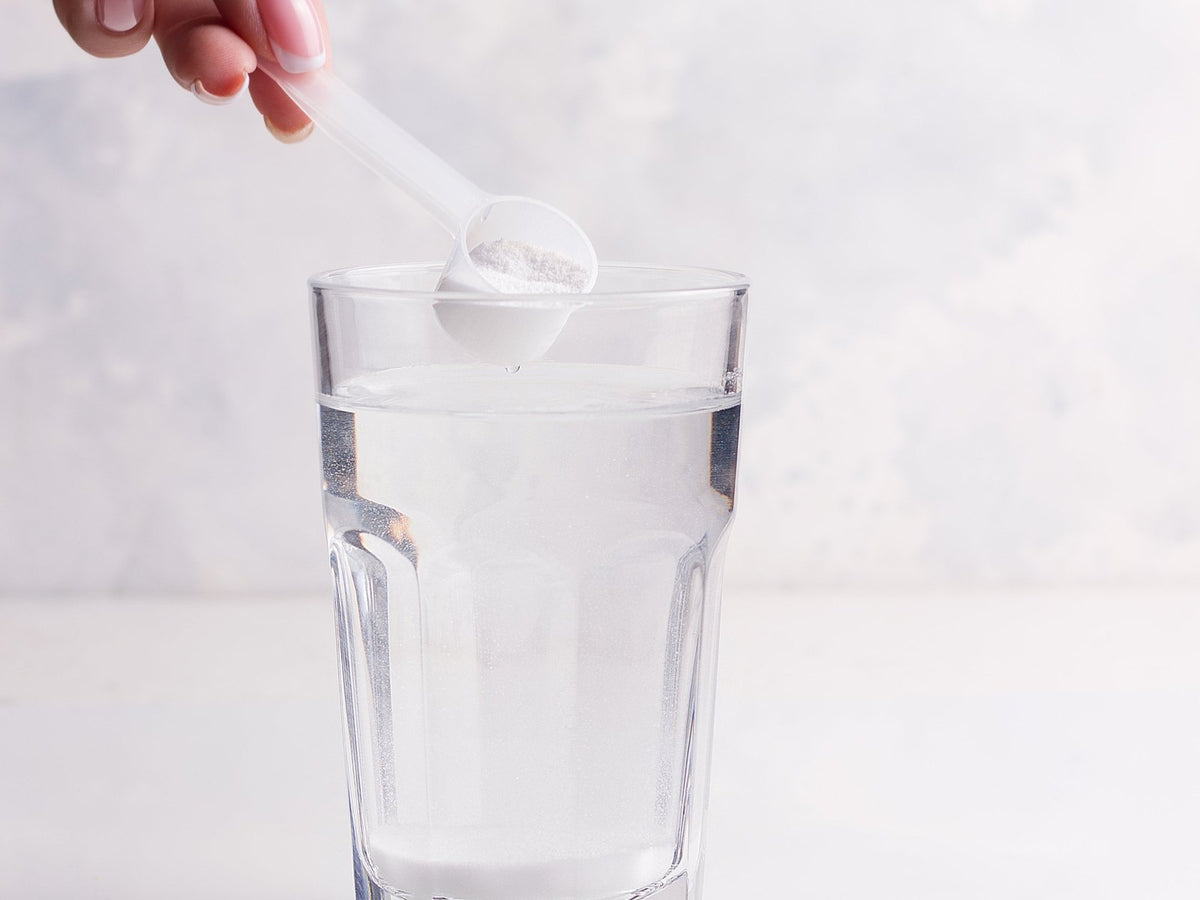 Scoop of white powder over a glass of water