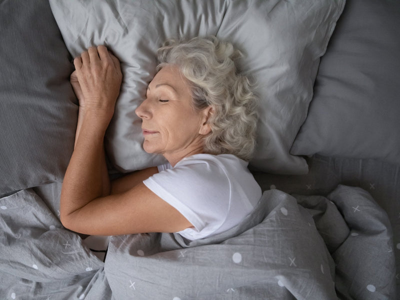 Woman sleeping peacefully on grey bedding